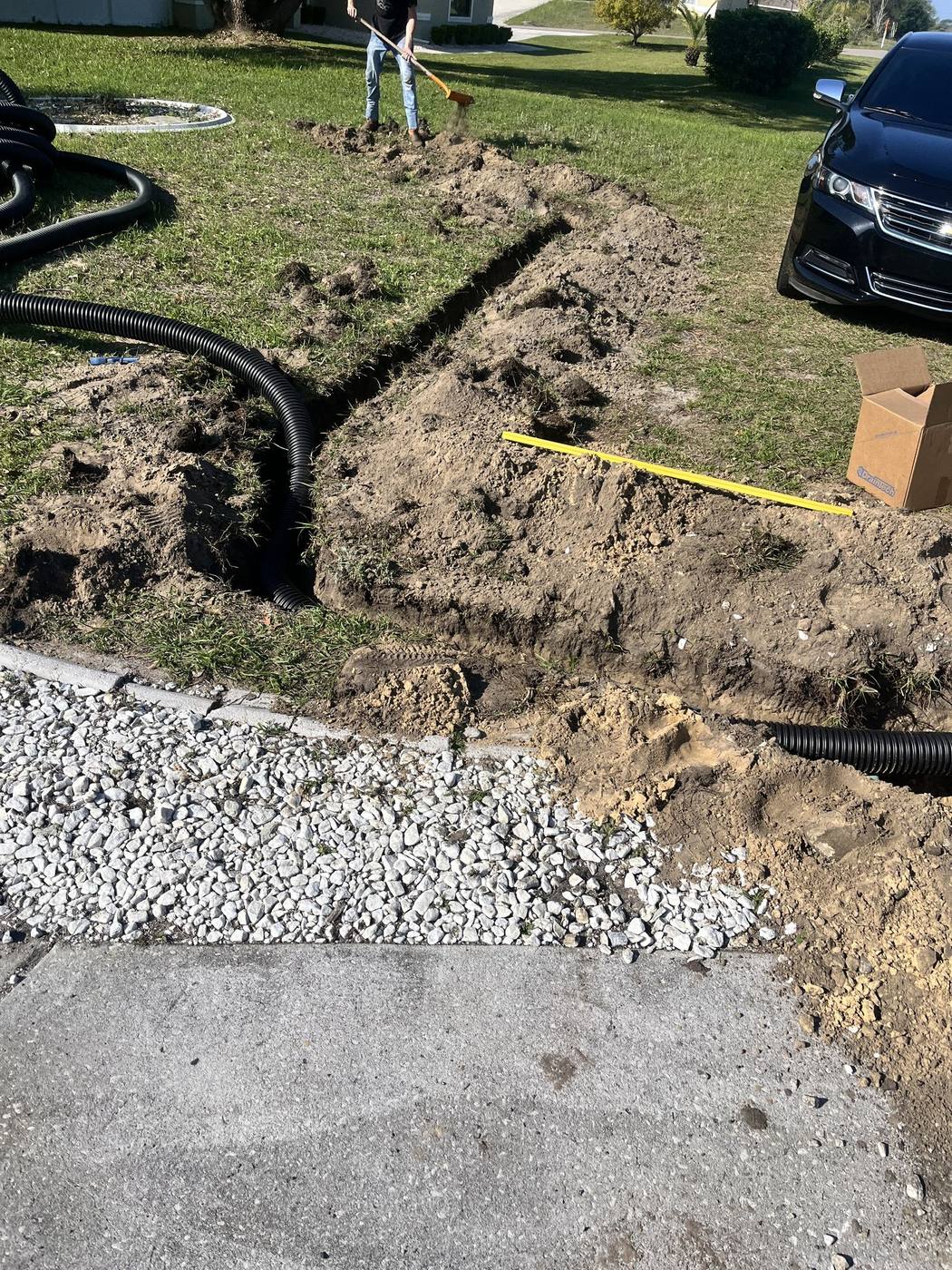 Reid's crew digging a drainage trench in a front yard between the driveway and street