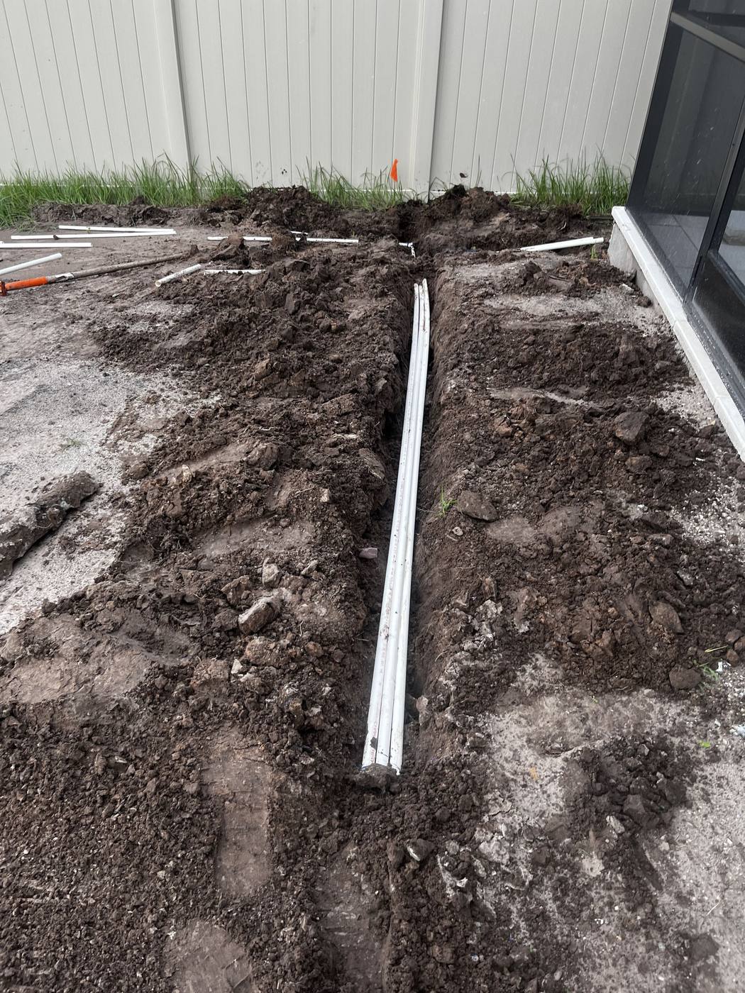 New irrigation supply line laid in a freshly dug trench along a fence line
